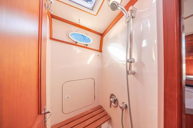 Slide: The Image of Shower area in 1999 Hinckley Talaria 44 Express yacht with wooden accents and porthole window. - 46