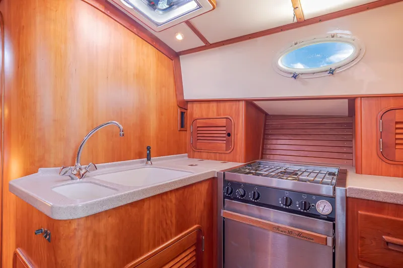Slide: The Image of Hinckley Talaria 44 Express 1999 yacht kitchen with wood cabinetry and stainless steel stove. - 31