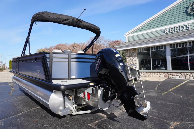Slide: The Image of 2026 Viaggio Lago V-R pontoon boat with Mercury outboard motor, parked outside dealership. - 2