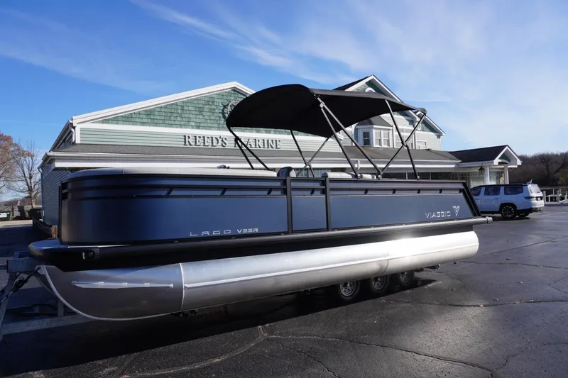 Slide: The Image of 2026 Viaggio Lago V-R pontoon boat parked at Reed's Marine dealership. - 68