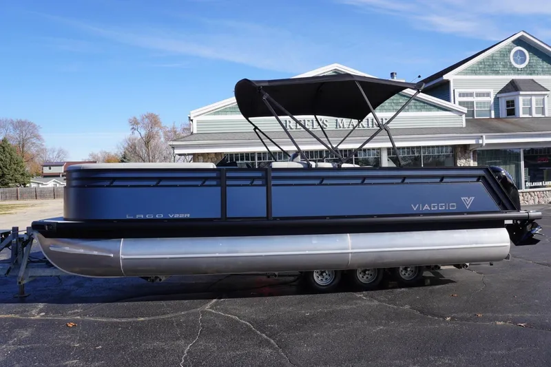 Slide: The Image of 2026 Viaggio Lago V-R pontoon boat parked outside a marine dealership. - 69