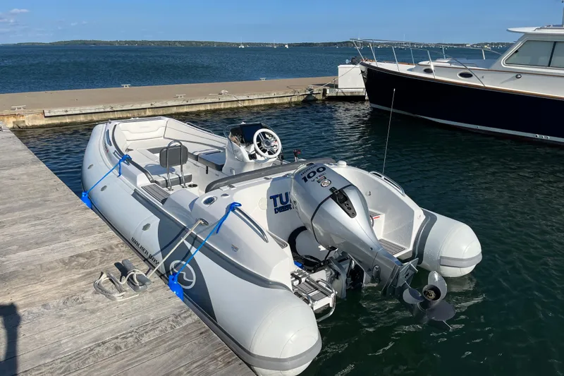 Slide: The Image of 2022 Walker Bay Generation 525 DLX boat docked at a marina, featuring a powerful outboard motor. - 3