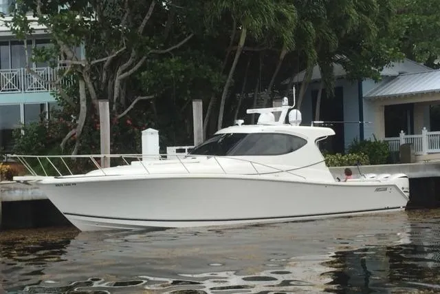Slide: The Image of 2015 Jupiter 41 SB boat docked near waterfront homes and lush greenery. - 15
