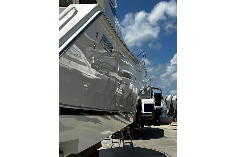 Slide: The Image of 2015 Jupiter 41 SB boat reflecting sunlight, docked under a clear blue sky. - 52