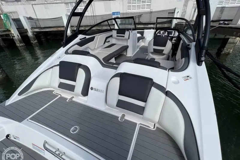 Slide: The Image of 2022 Yamaha Boats AR210 interior with sleek seating and modern design at a dock. - 2