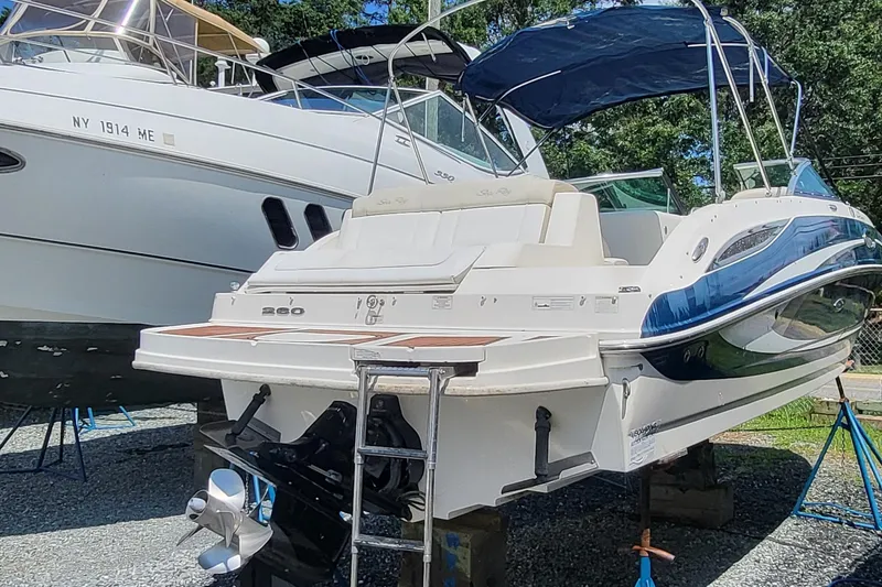 Slide: The Image of 2013 Sea Ray 260 Sundeck boat on stands, with blue canopy and sleek design. - 18