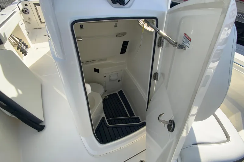 Slide: The Image of 2026 Cobia 285 Center Console boat interior with open door to compact restroom. - 39