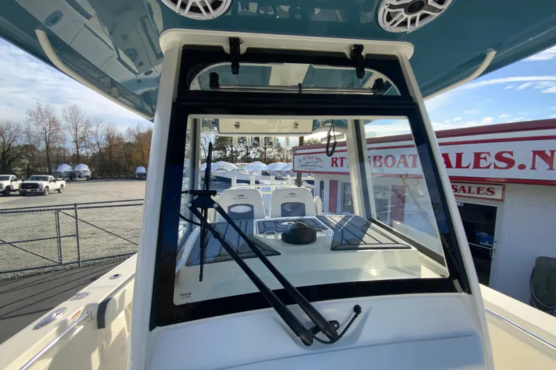 Slide: The Image of 2026 Cobia 285 Center Console boat at dealership, showcasing helm and windshield. - 44
