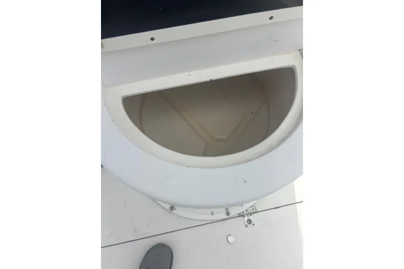 Slide: The Image of 1998 Mako 221 Center Console boat storage compartment, white interior, open lid. - 9