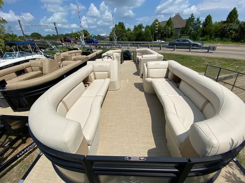 Slide: The Image of 2021 Harris 250 Cruiser pontoon boat with spacious seating, parked outdoors under a blue sky. - 12