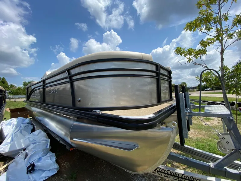 Slide: The Image of 2021 Harris 250 Cruiser pontoon boat on trailer under a partly cloudy sky. - 13