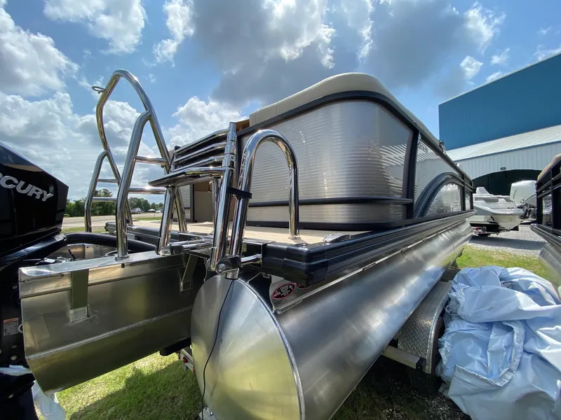 Slide: The Image of 2021 Harris 250 Cruiser pontoon boat with stainless steel rails, parked outdoors under a cloudy sky. - 3