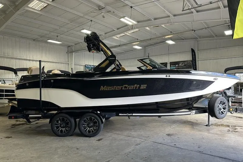 Slide: The Image of 2025 MasterCraft XT24 boat in a showroom, black and white design on trailer. - 10