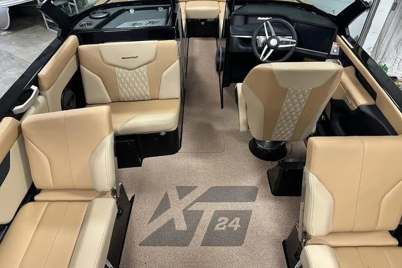 Slide: The Image of 2025 MasterCraft XT24 boat interior with beige seating and steering wheel. - 29