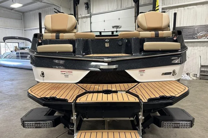 Slide: The Image of 2025 MasterCraft XT24 boat with tan seating and wooden deck in a showroom. - 4