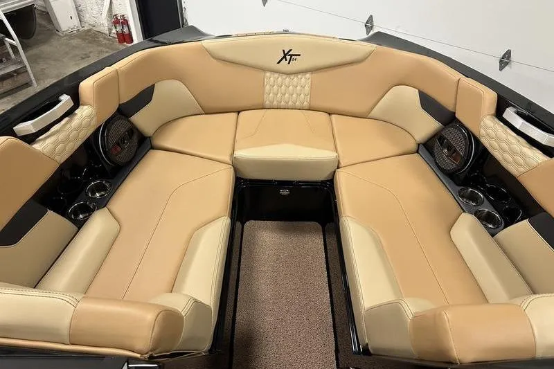 Slide: The Image of 2025 MasterCraft XT24 boat interior with tan leather seating and cup holders. - 47