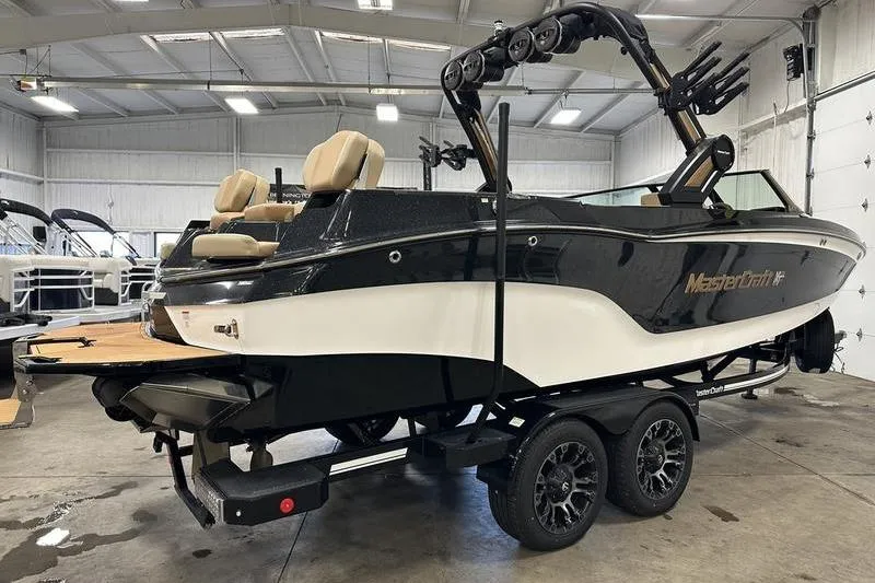 Slide: The Image of 2025 MasterCraft XT24 boat in showroom, black and white design, on trailer. - 5