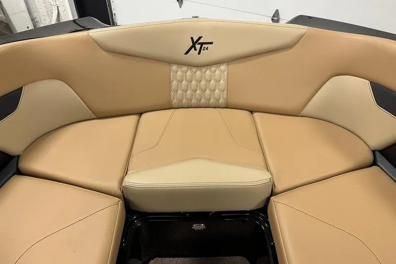 Slide: The Image of 2025 MasterCraft XT24 boat interior with tan leather seating and logo. - 53