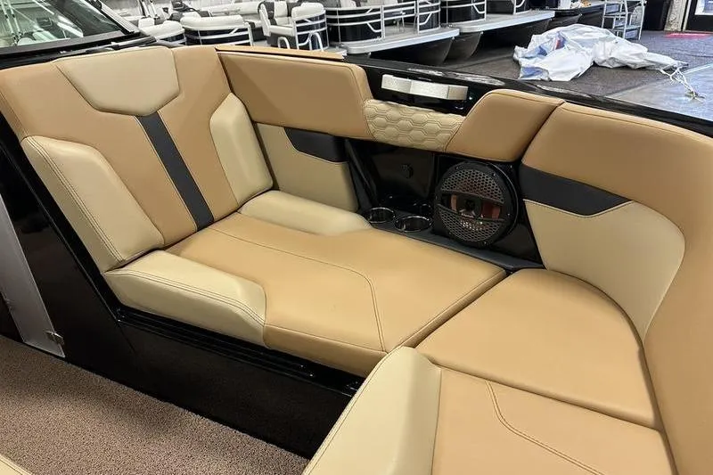 Slide: The Image of 2025 MasterCraft XT24 boat interior with tan and black seating, featuring a speaker and cup holders. - 54