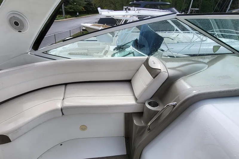 Slide: The Image of 2008 Cruisers 330 boat interior with white seating and cup holder, docked near other boats. - 10