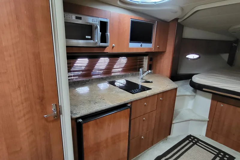 Slide: The Image of 2008 Cruisers 330 yacht interior with kitchenette, featuring microwave, stove, and sink. - 14