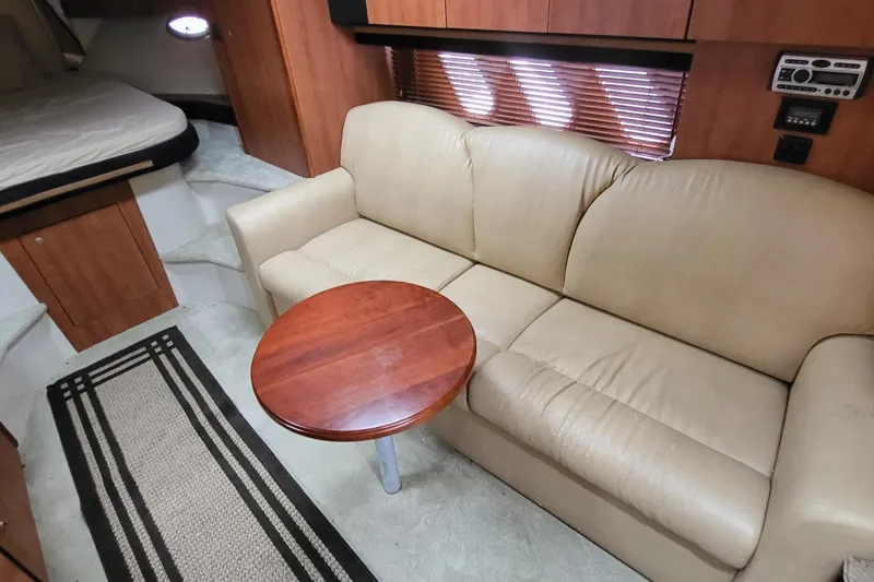 Slide: The Image of 2008 Cruisers 330 yacht interior with beige sofa, wooden table, and cozy cabin space. - 15
