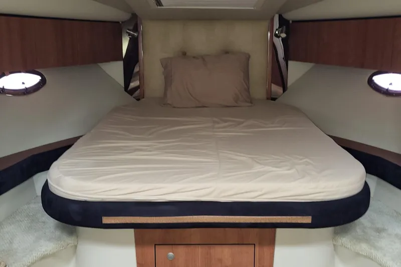 Slide: The Image of 2008 Cruisers 330 boat cabin with a cozy bed and wooden accents. - 13