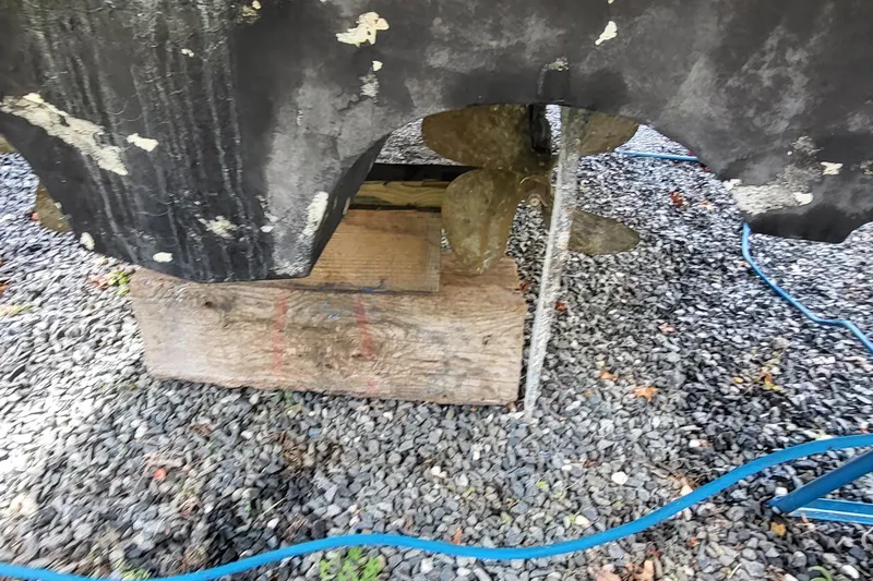 Slide: The Image of 2008 Cruisers 330 boat propeller and hull on gravel with blue hose. - 20