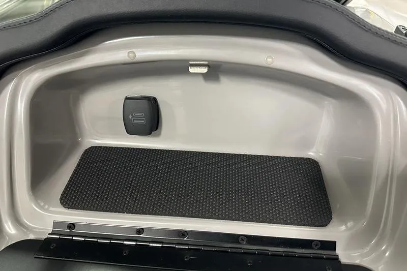 Slide: The Image of Storage compartment in a 2026 Chaparral 21 SSi boat, featuring a secure latch and rubber mat. - 2