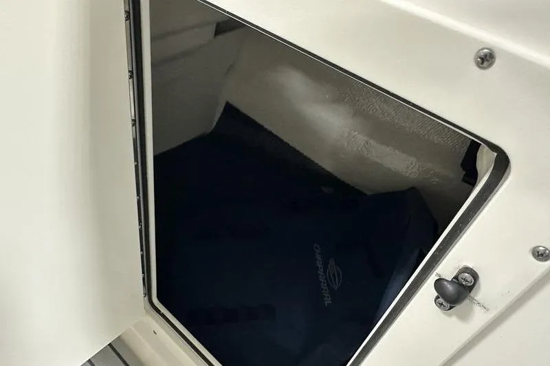 Slide: The Image of Storage compartment in 2026 Chaparral 21 SSi boat, featuring secure latch and interior space. - 25