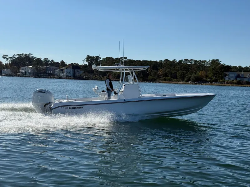 Slide: The Image of 2026 Contender 29 Bay boat cruising on a sunny day, with scenic waterfront homes in the background. - 7