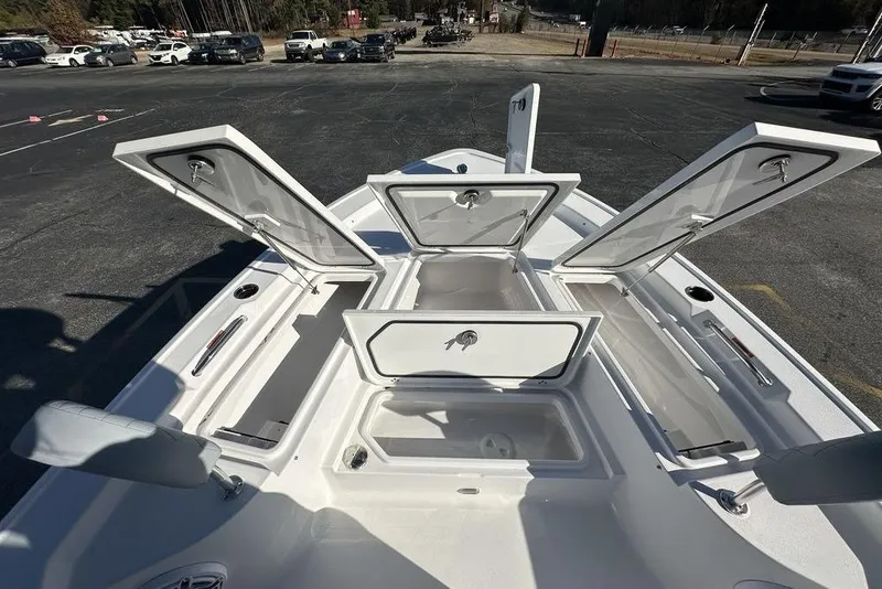 Slide: The Image of 2026 Sportsman Masters 227 Bay Boat with open storage compartments, parked outdoors. - 16
