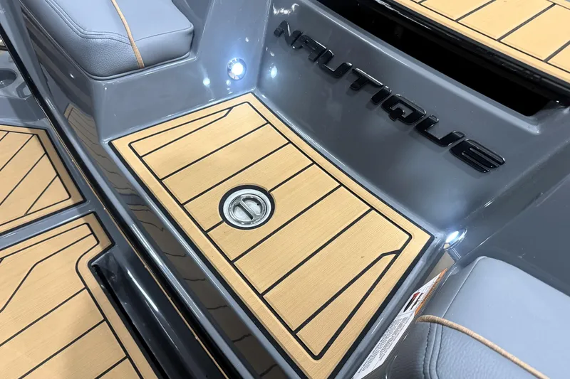 Slide: The Image of 2026 Nautique Super Air Nautique S21 boat interior with teak flooring and logo detail. - 25