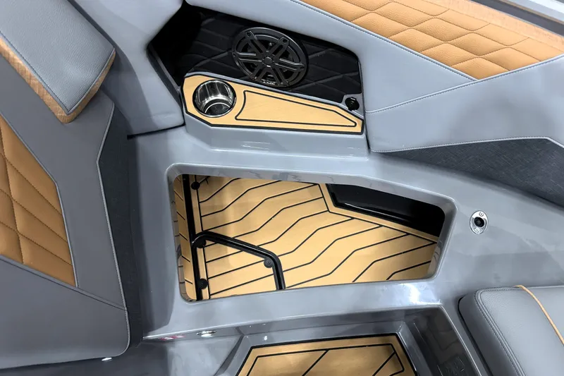 Slide: The Image of 2026 Nautique Super Air Nautique S21 interior with tan and gray upholstery, cup holder, and speaker. - 30