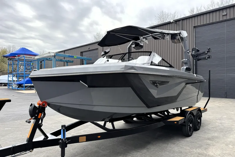 Slide: The Image of 2026 Nautique Super Air Nautique S21 boat on trailer, parked outside industrial building. - 4
