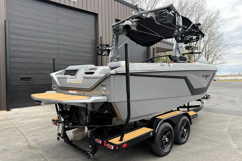 Slide: The Image of 2026 Nautique Super Air Nautique S21 boat on trailer, parked near industrial building. - 7