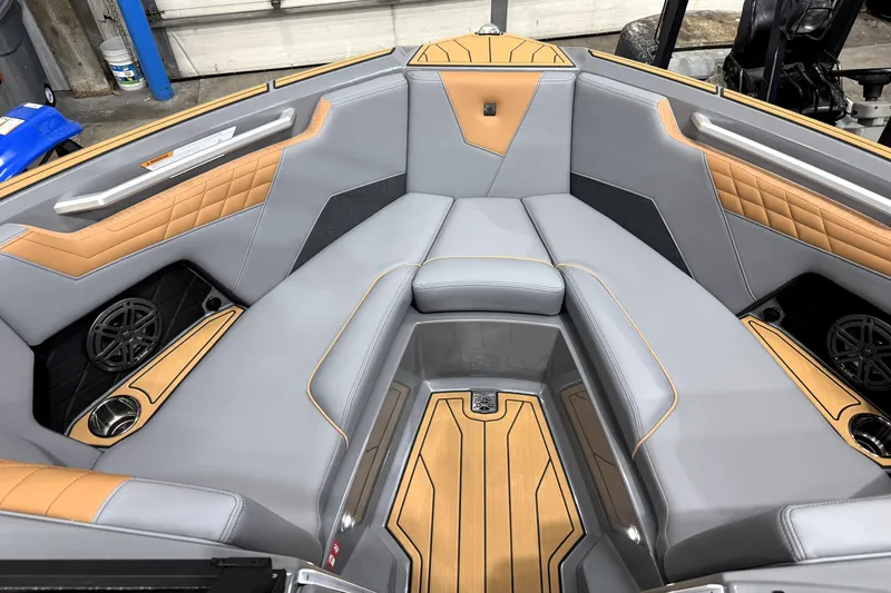 Slide: The Image of 2026 Nautique Super Air Nautique S21 interior with gray and tan upholstery, featuring speakers and cup holders. - 9