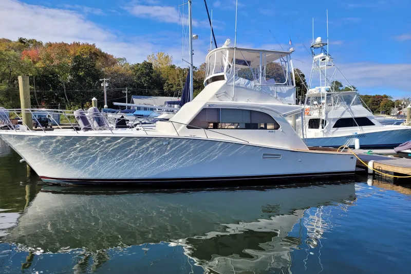 The Image of 1985 Post 43 Convertible yacht docked in a marina, reflecting on calm water. - 0