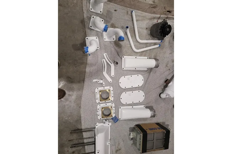 Slide: The Image of Assorted white mechanical parts for 1985 Post 43 Convertible on a gray surface. - 16