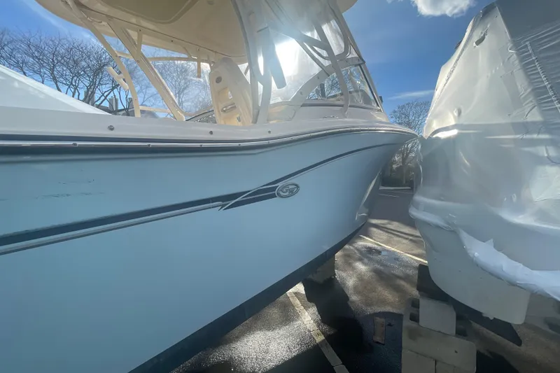 Slide: The Image of 2018 Grady-White Freedom 235 boat in sunlight, docked beside another vessel. - 12