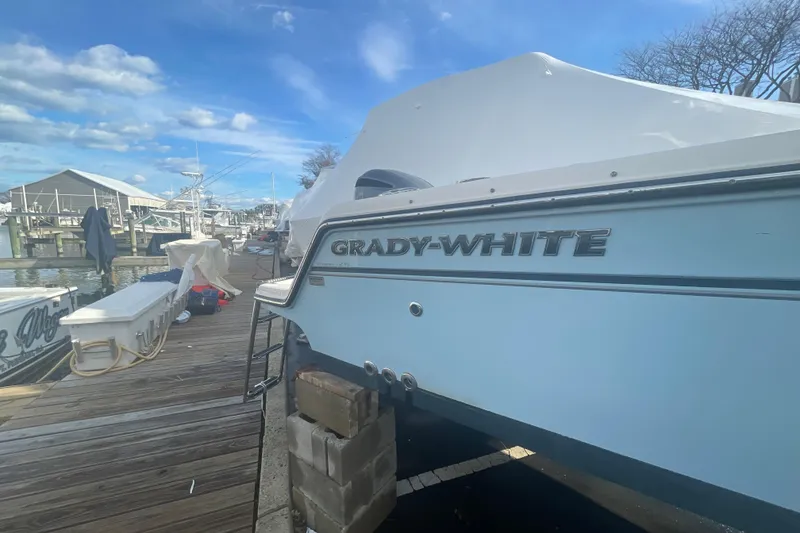 Slide: The Image of 2018 Grady-White Freedom 235 boat docked at marina under blue sky. - 13