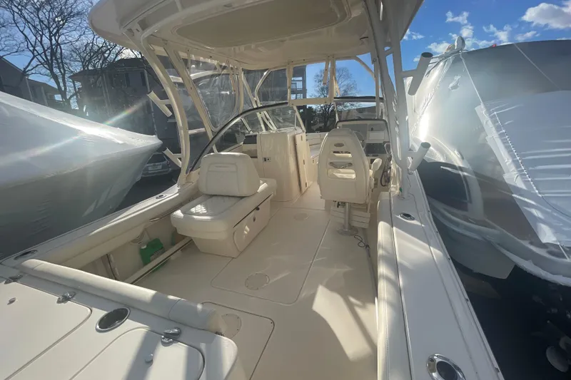 Slide: The Image of 2018 Grady-White Freedom 235 boat interior, featuring seating and helm, under sunny skies. - 24