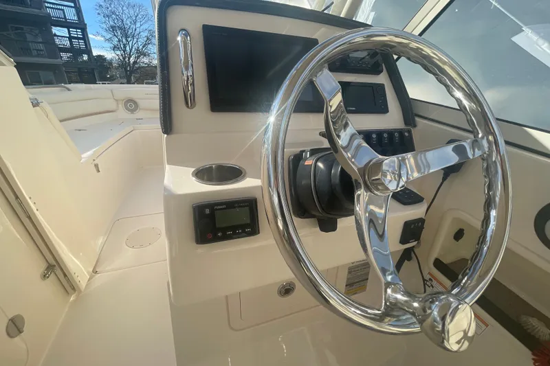 Slide: The Image of 2018 Grady-White Freedom 235 boat helm with chrome steering wheel and control panel. - 54