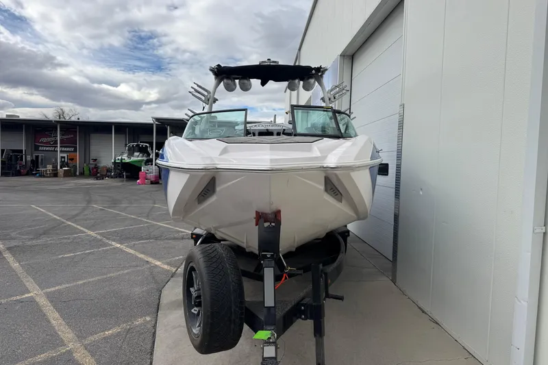 Slide: The Image of 2020 Supra SL 575 boat on trailer, parked outside a building under cloudy skies. - 10