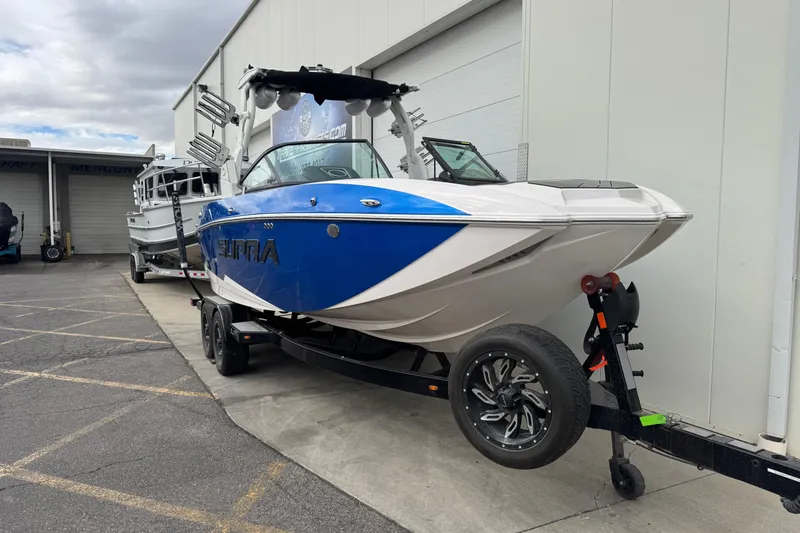 Slide: The Image of 2020 Supra SL 575 boat on trailer, blue and white design, parked outside a building. - 4