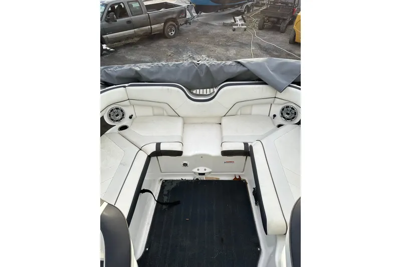 Slide: The Image of 2016 Yamaha Boats 212SS interior with white seating and speakers, parked outdoors. - 15