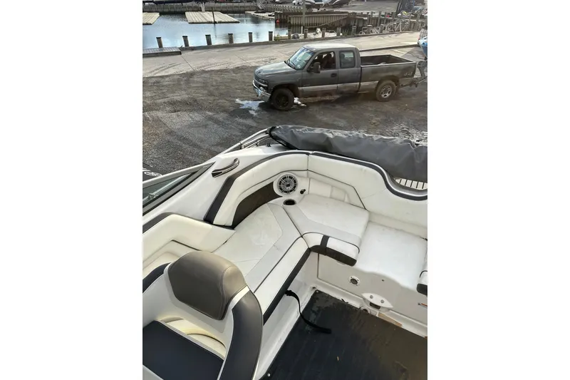 Slide: The Image of 2016 Yamaha Boats 212SS interior with seating, docked near a pickup truck. - 16