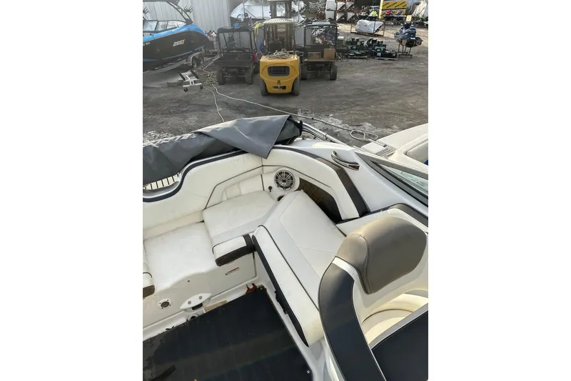Slide: The Image of 2016 Yamaha Boats 212SS interior with white seating and speaker, parked outdoors. - 19