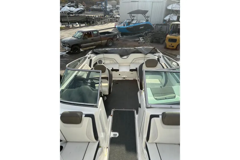 Slide: The Image of 2016 Yamaha Boats 212SS interior view at a marina with surrounding vehicles. - 21