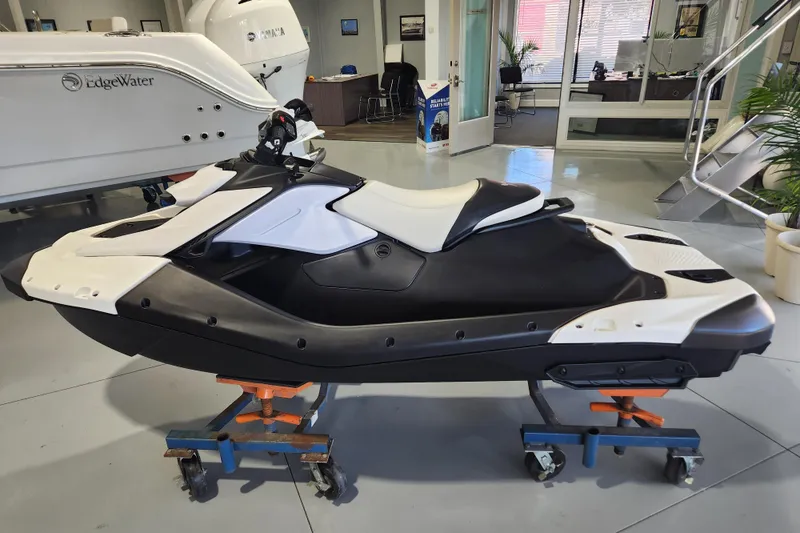 The Image of 2024 Sea-Doo Spark Trixx jet ski on a trailer in a showroom. - 0
